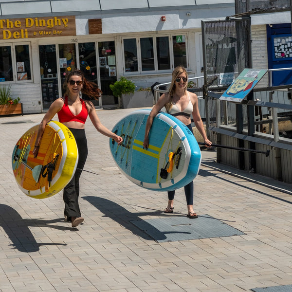 women carrying paddle boards